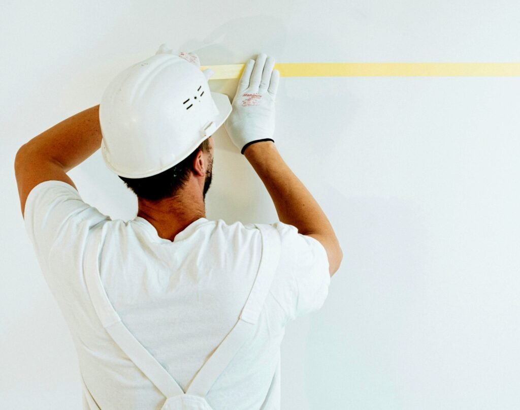 Pintor profesional colocando cinta de carrocero en la pared, mejor práctica para un buen acabado de pintura